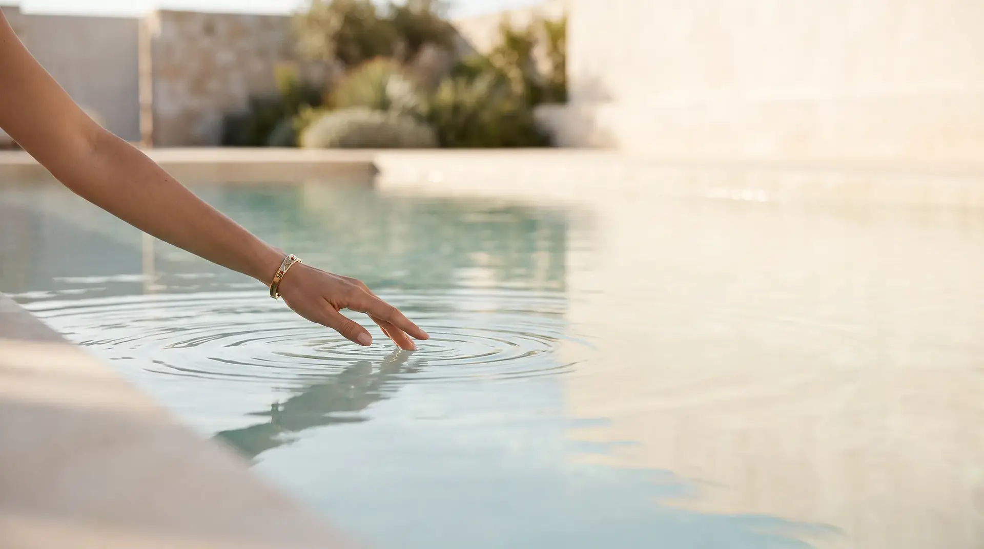 A hand touching still pool water